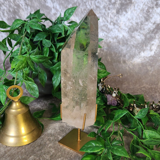 Polished clear quartz crystal point from Brazil displayed on metal stand
