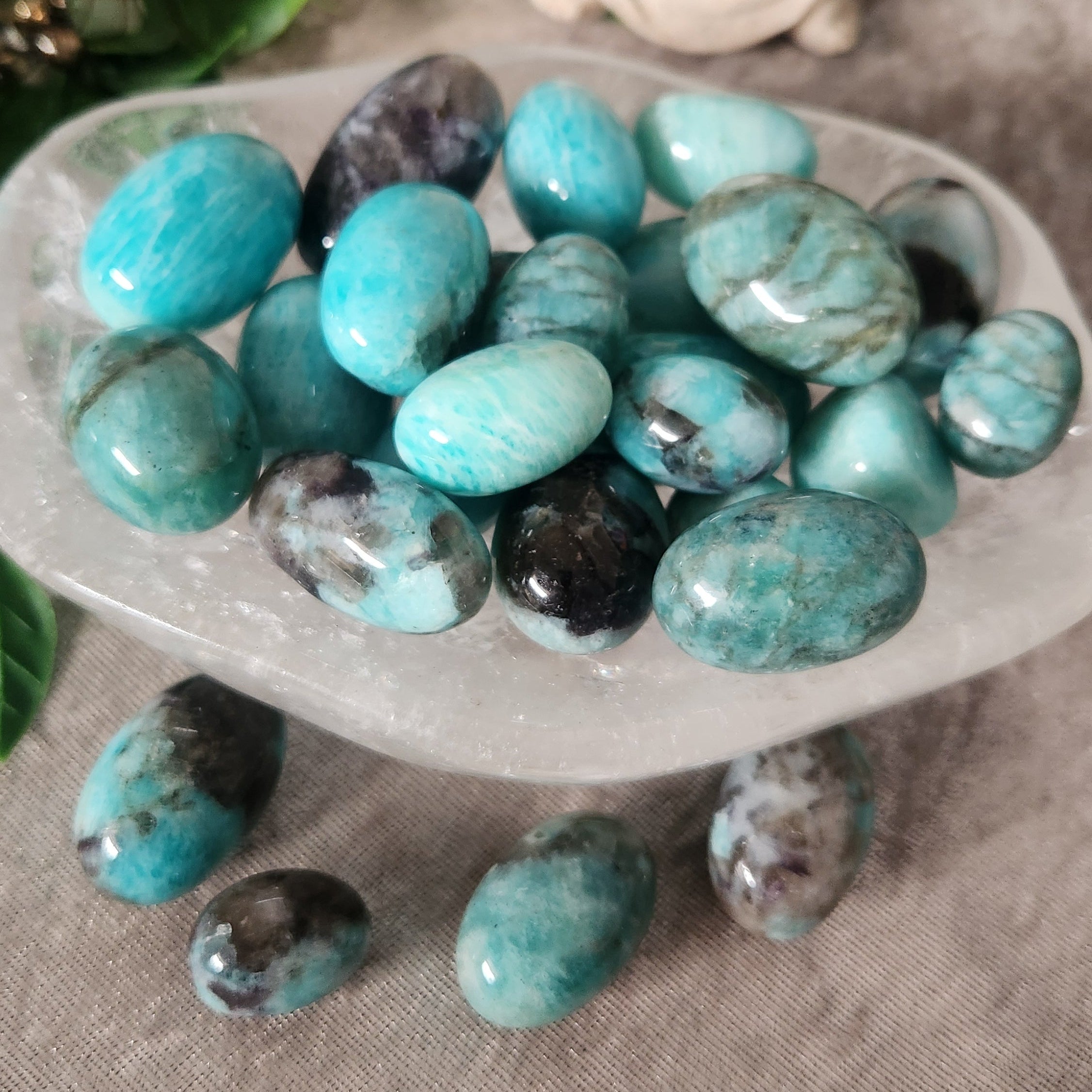 Polished Smoky Amazonite tumbles arranged on a white surface, showing their unique smoky veining.
