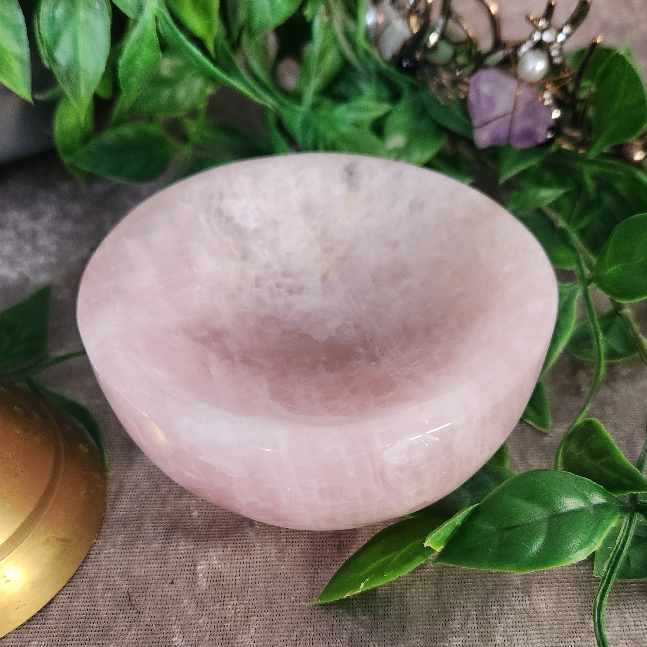 Rose quartz crystal bowl displayed with greenery, polished pink stone for gentle energy and decor