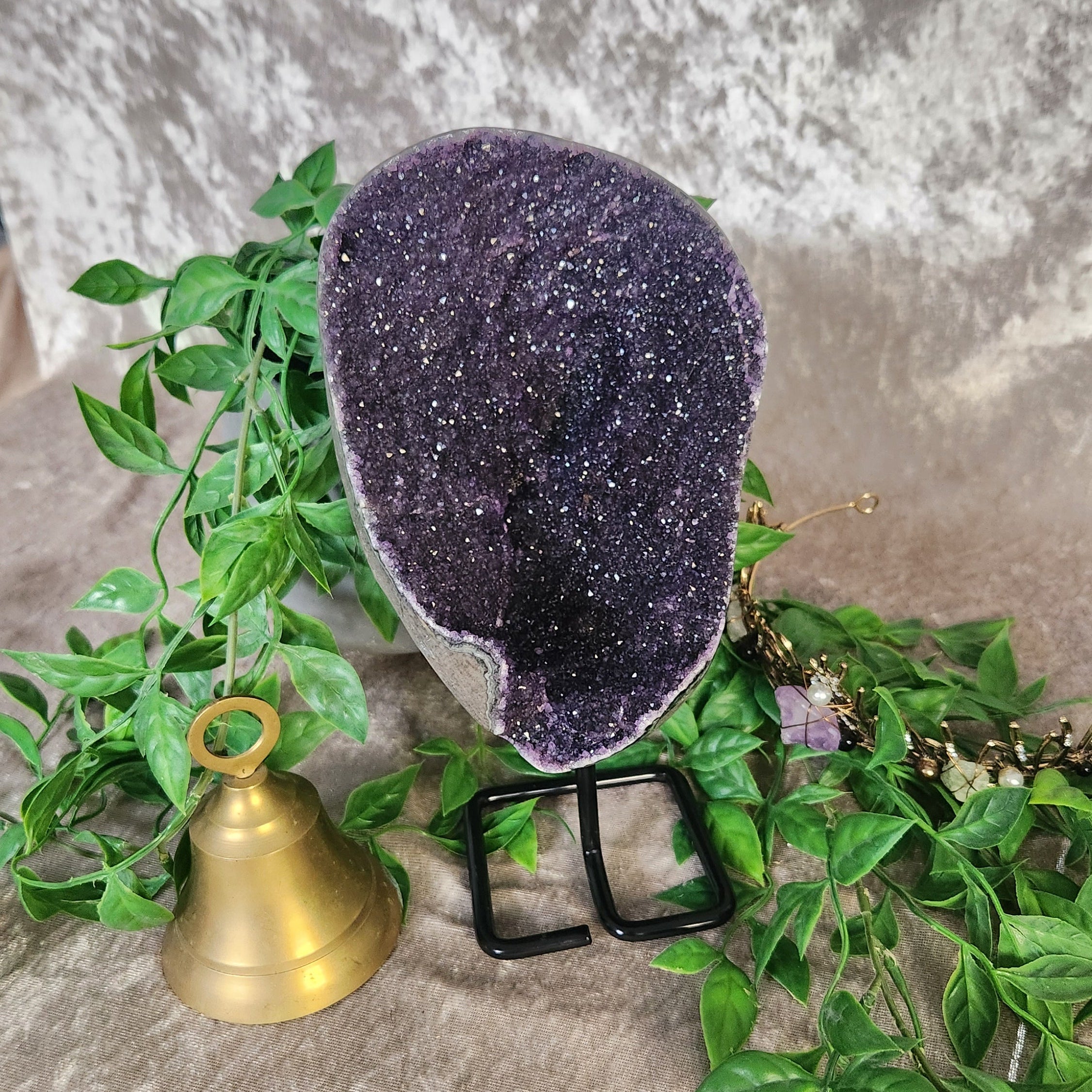 An abundance of sparkling Amethyst Galaxy on stand set in witchy decor setting