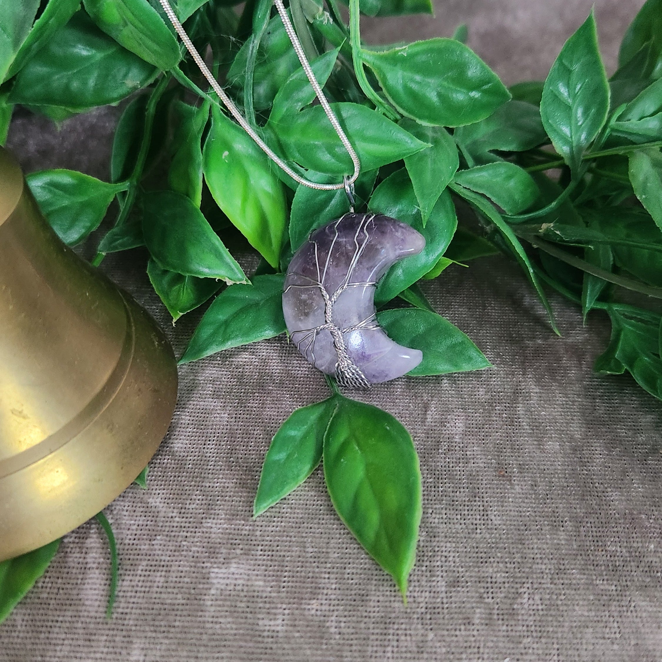 Hand wrapped amethyst moon pendant photographed for crystal jewellery