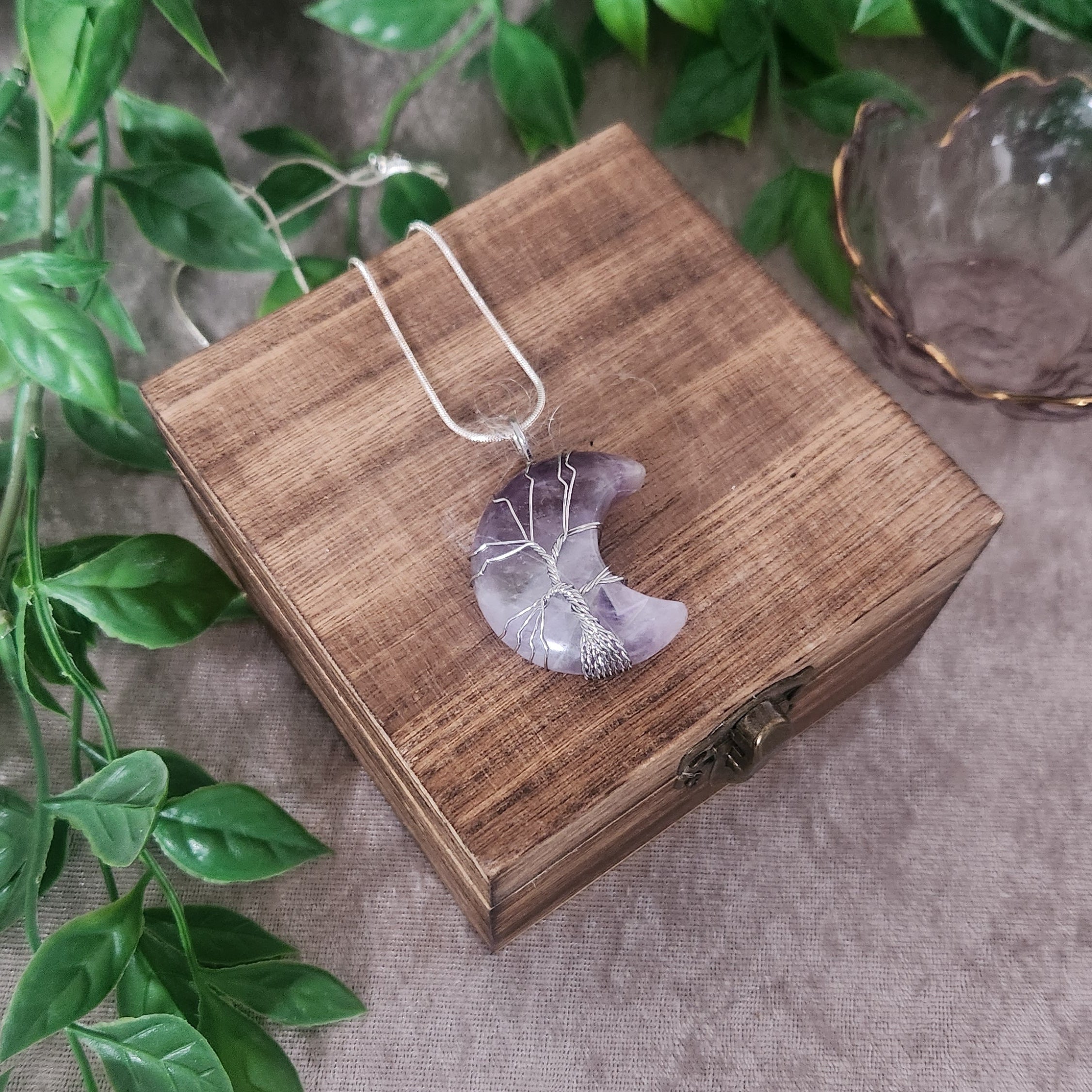 Amethyst moon necklace with silver wire wrap on teal background