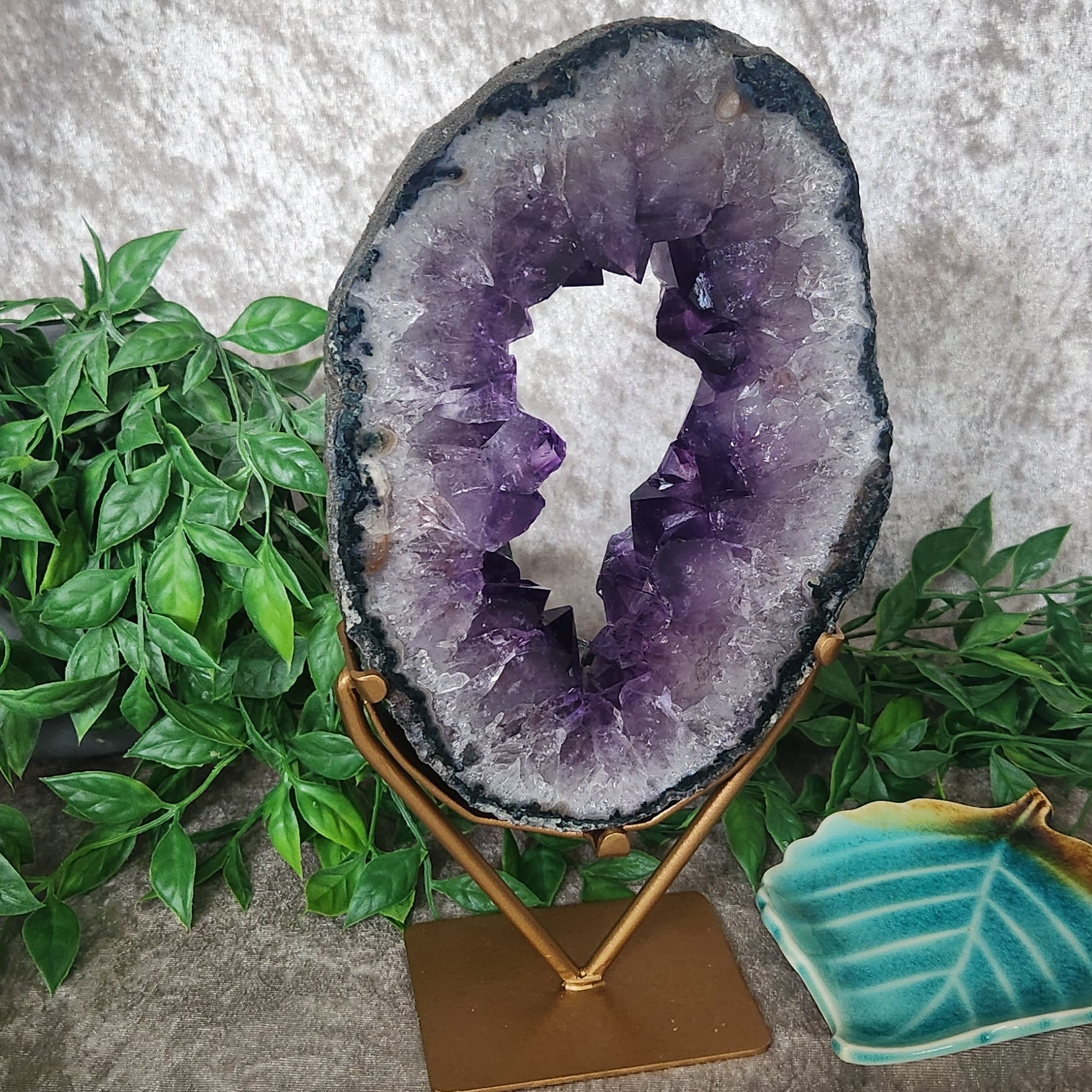 Amethyst crystal portal on gold stand styled with greenery as a decorative home or altar feature