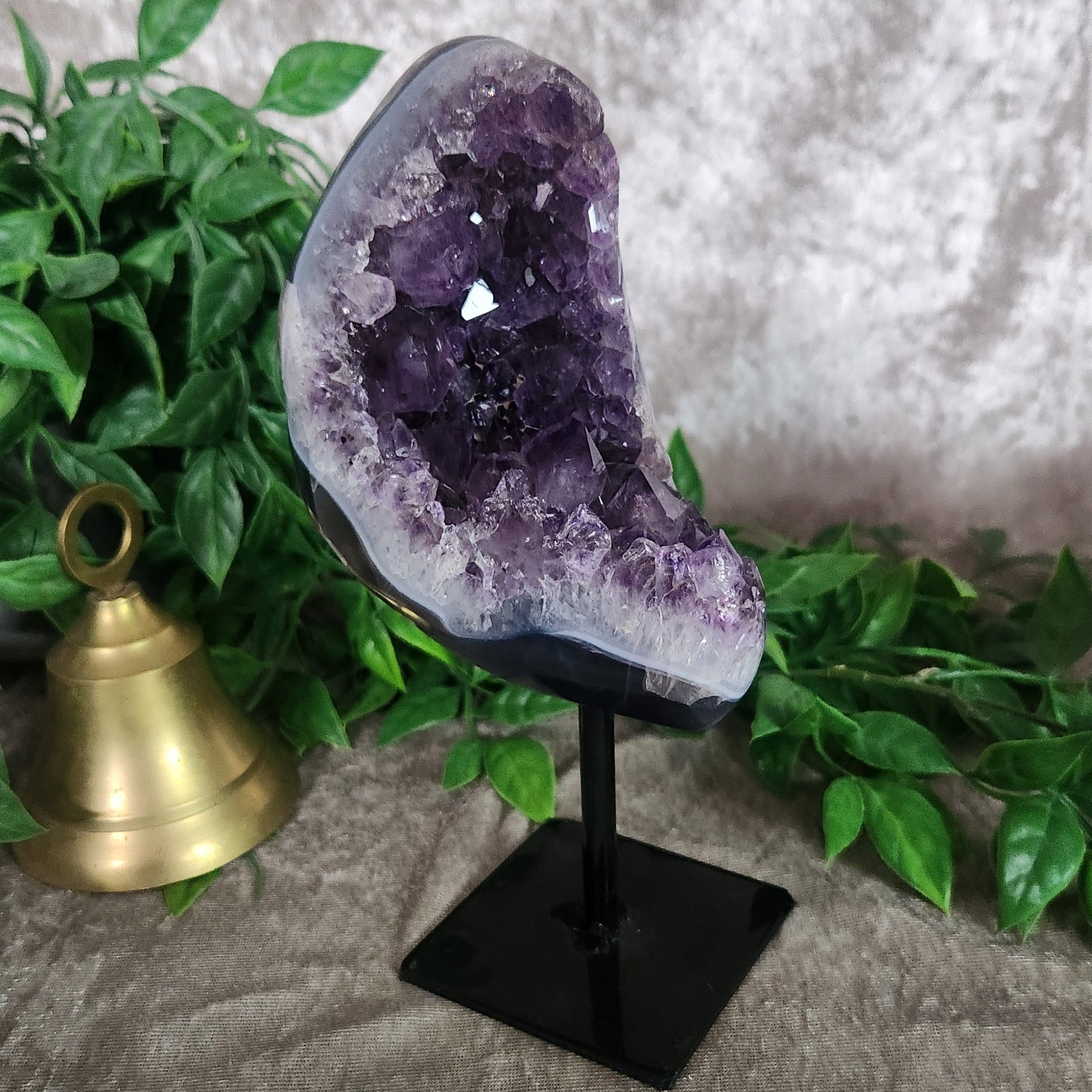 Side view of amethyst crystal geode on stand showing layered druzy formation and natural banding