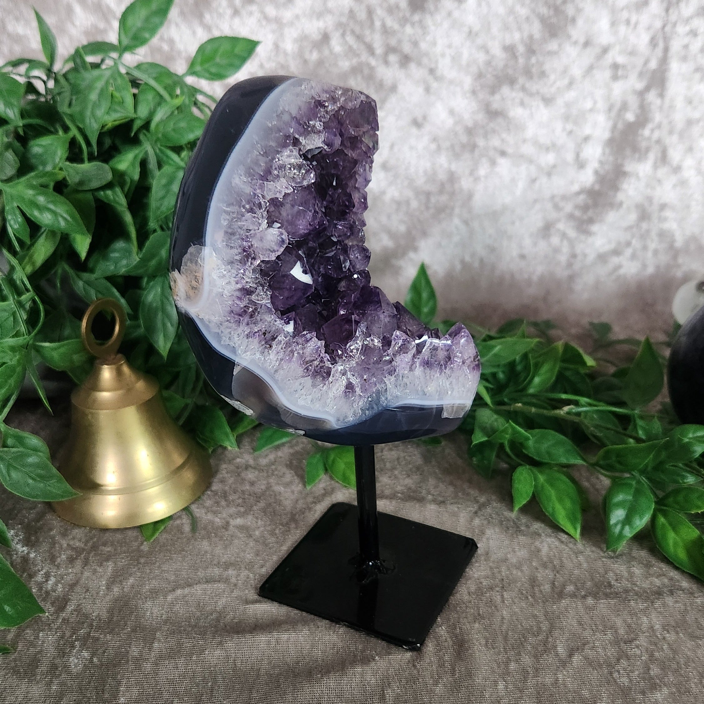 Amethyst druzy geode on black metal stand featuring deep purple crystal points and polished agate edge