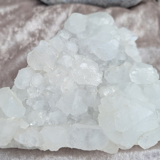 Sparkling white apophylite cluster displayed on a light bronze velvet