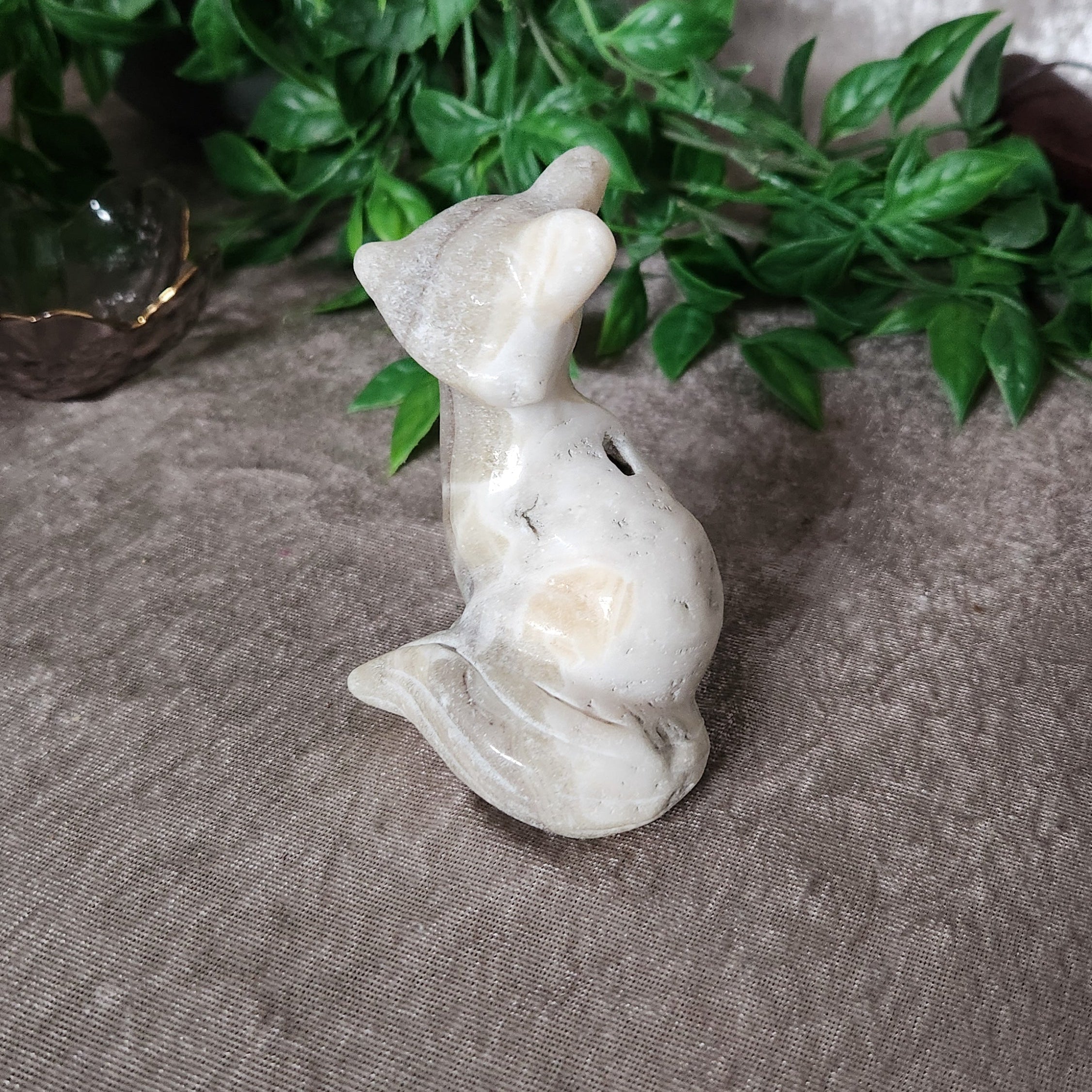 Banded calcite fox carving with cream and beige natural banding on neutral background
