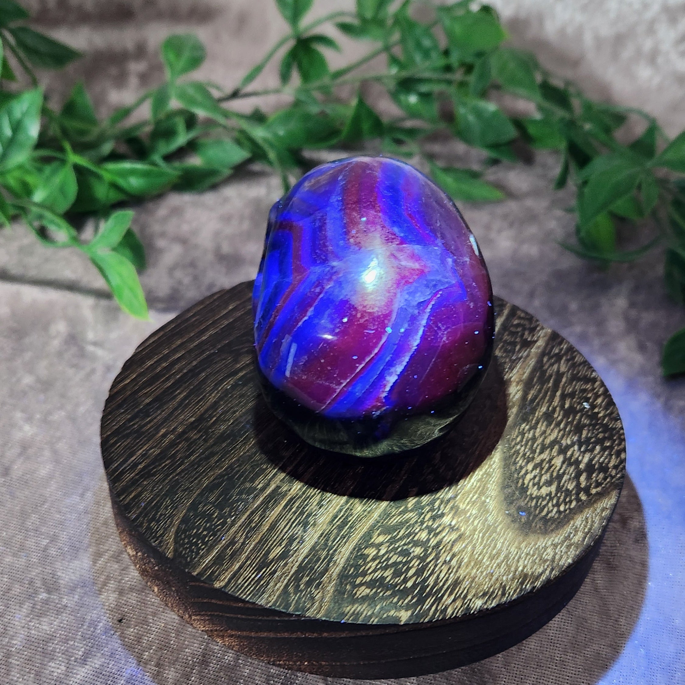UV-lit fluorite skull — top angle displaying dramatic colour bands and intense reactive glow.