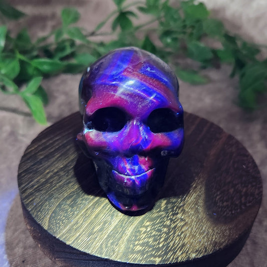 UV-reactive Black Rose Fluorite skull glowing with neon pink and violet fluorescence — front angle.