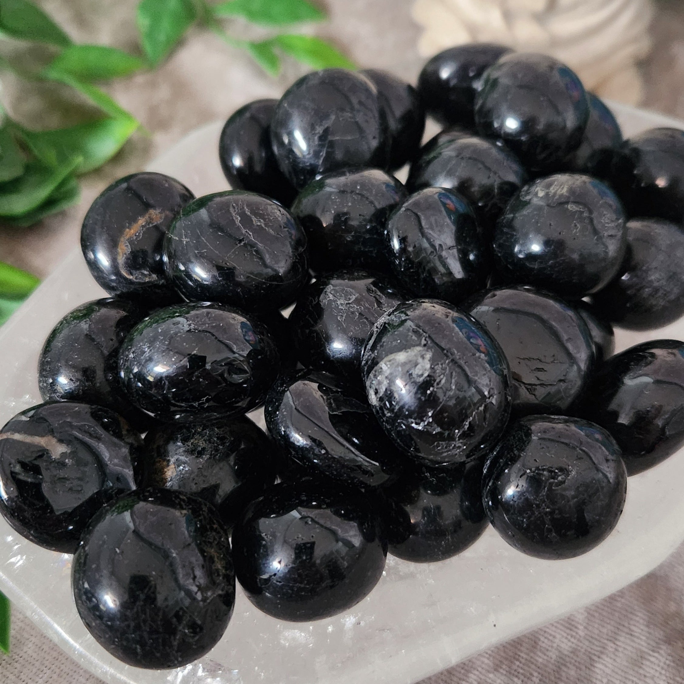 Black Tourmaline tumbled crystal with visible natural lines on decorative dish for grounding energy