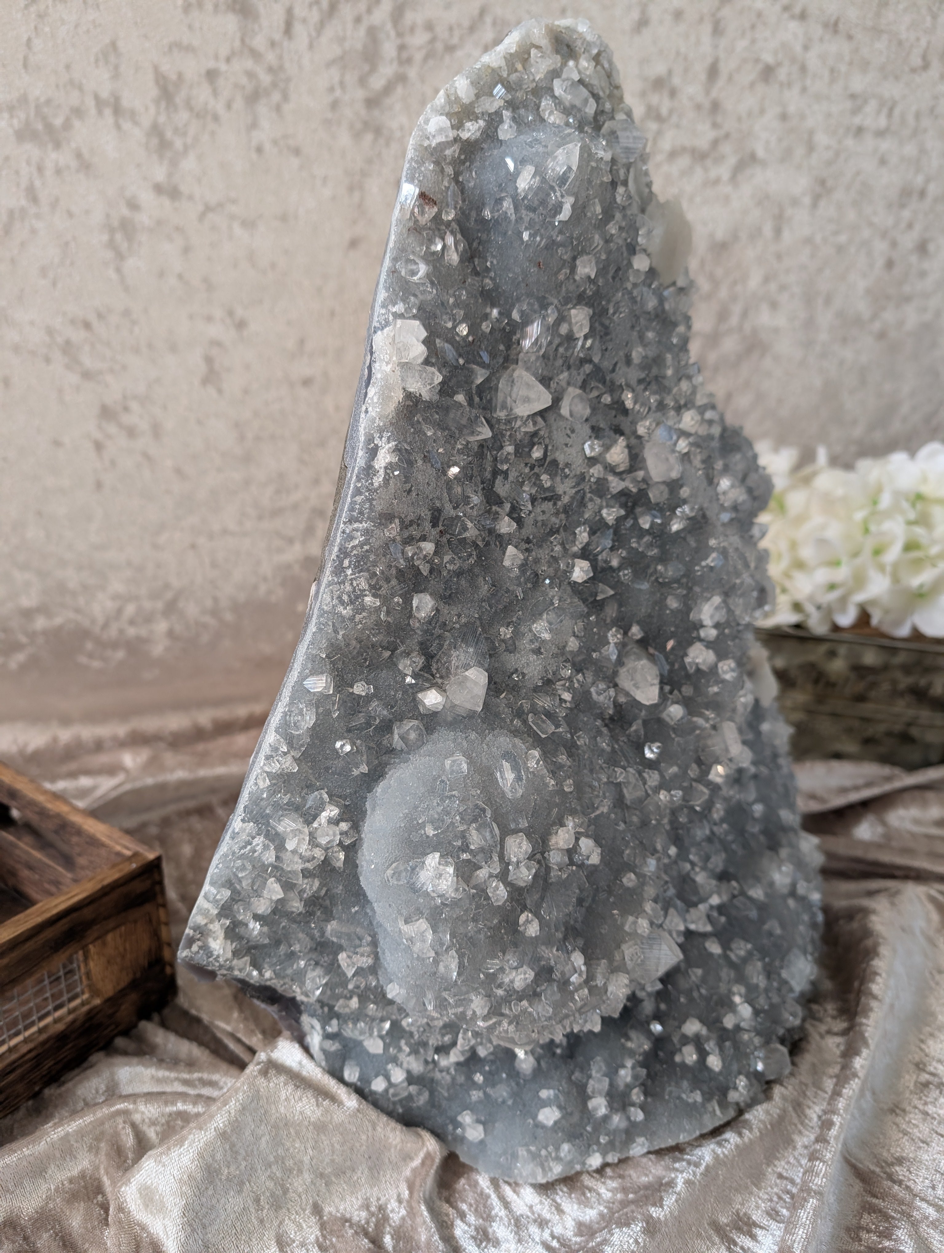 Chalcedony with Apophyllite and Zeolite displayed with white flowers in antique style tin and old style wooden crate