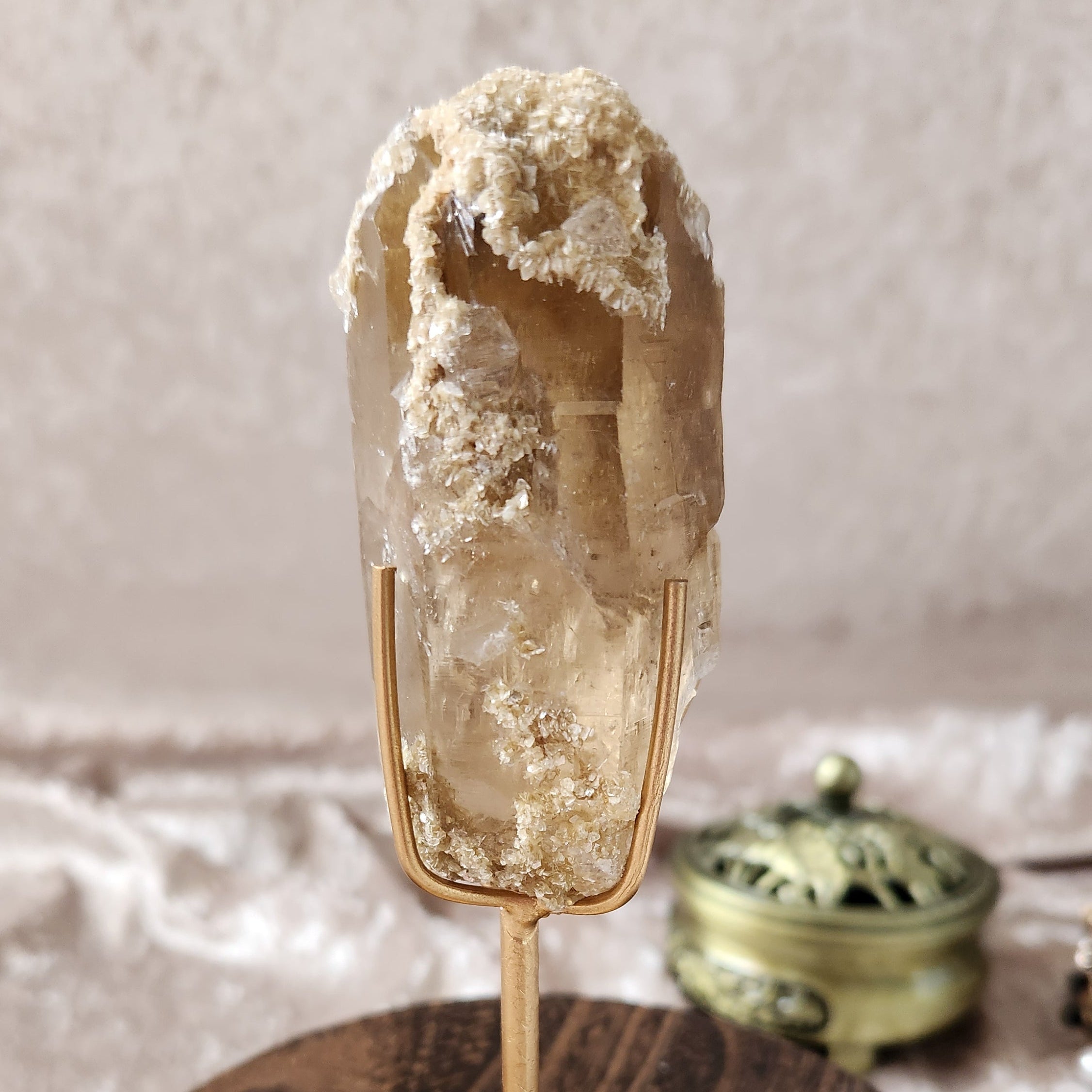 Brazilian citrine specimen with golden mica inclusions displayed on a metal stand