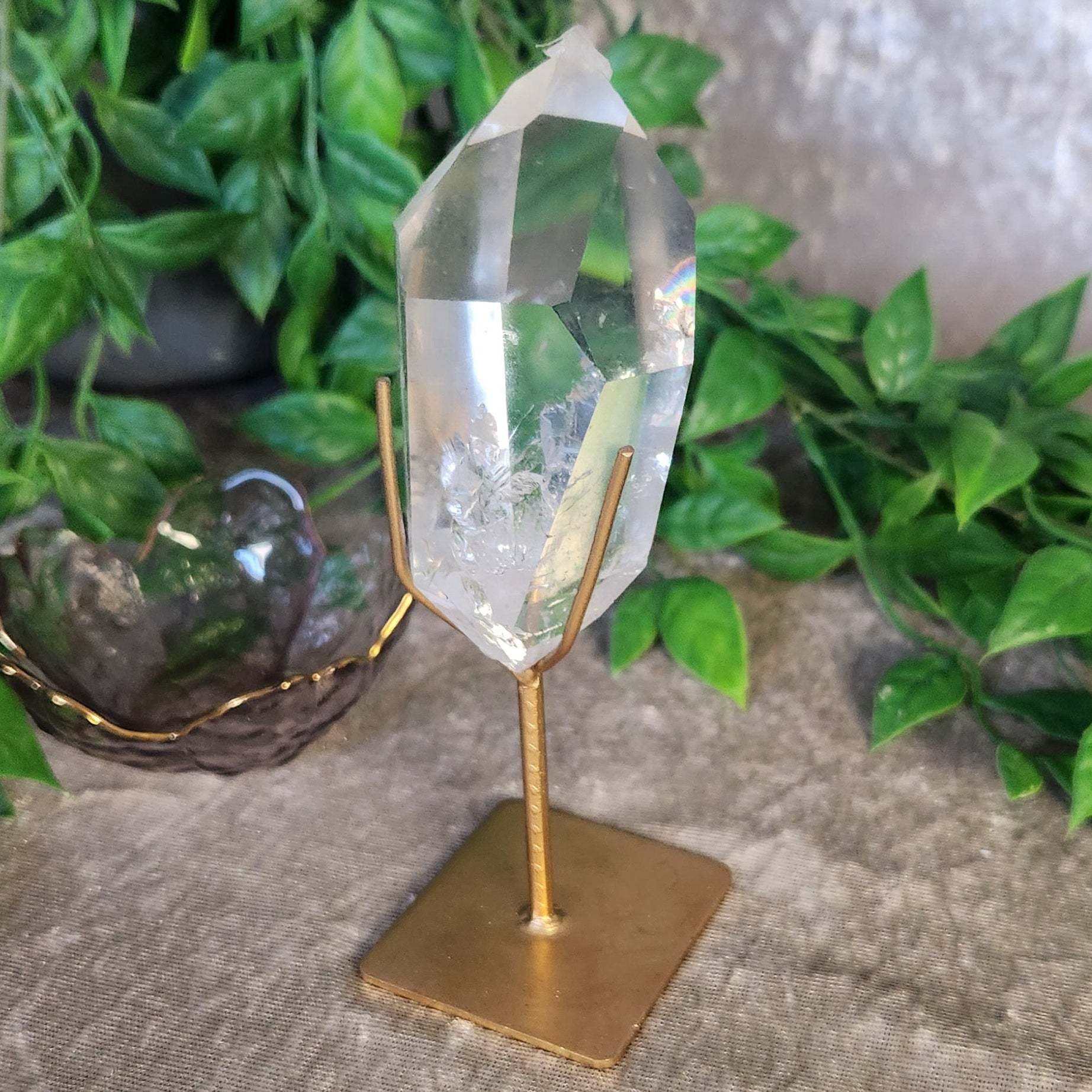 Clear quartz crystal point from Brazil displayed on gold metal stand