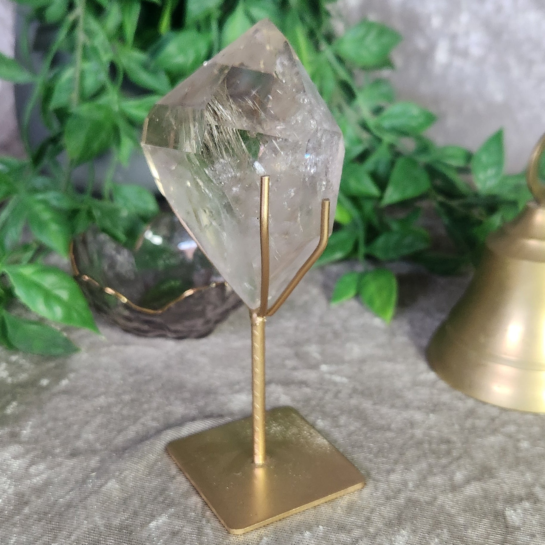 Detailed perspective of clear quartz with rutile inclusions mounted on stand, emphasizing natural energy and glow.