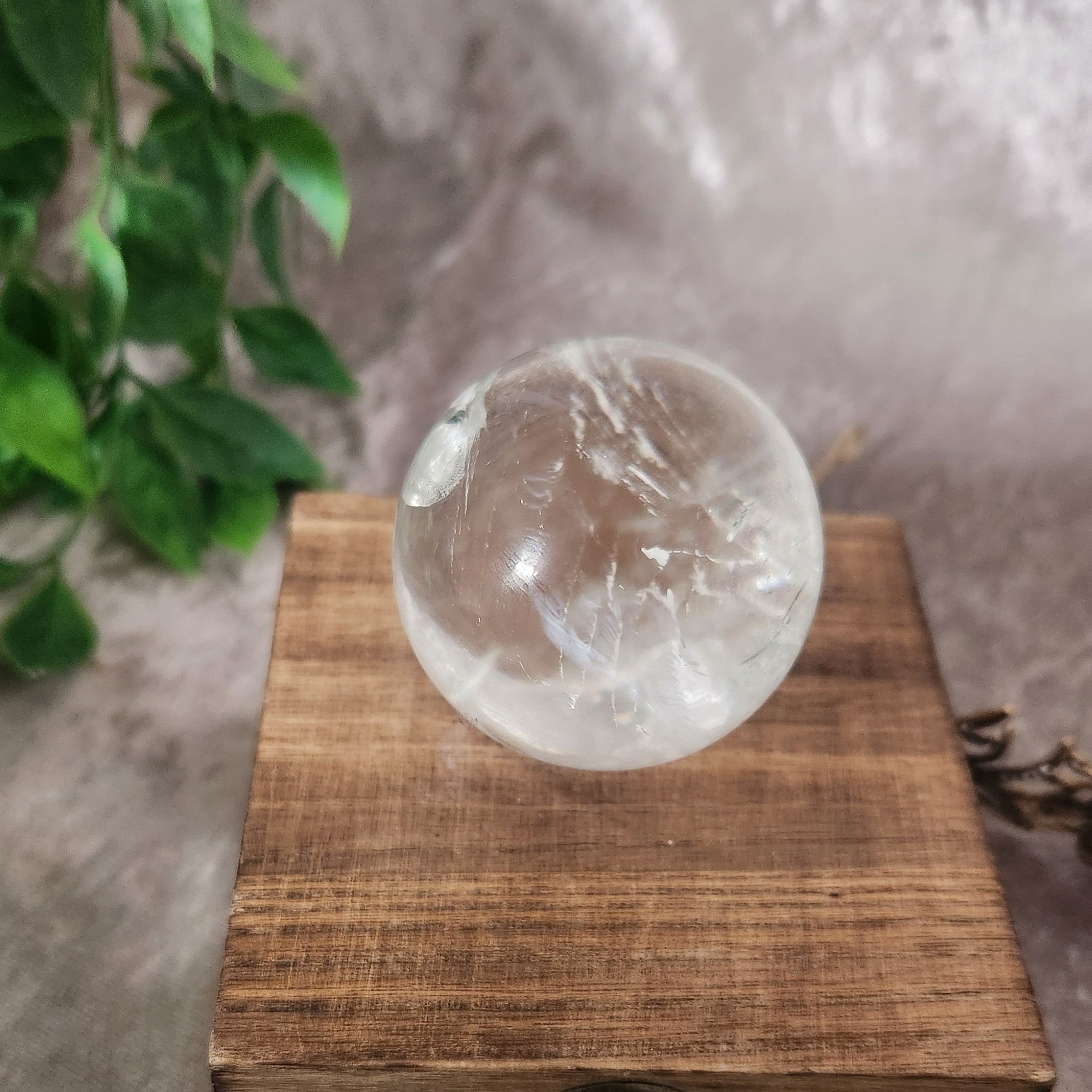 Clear quartz crystal ball reflecting light on neutral background