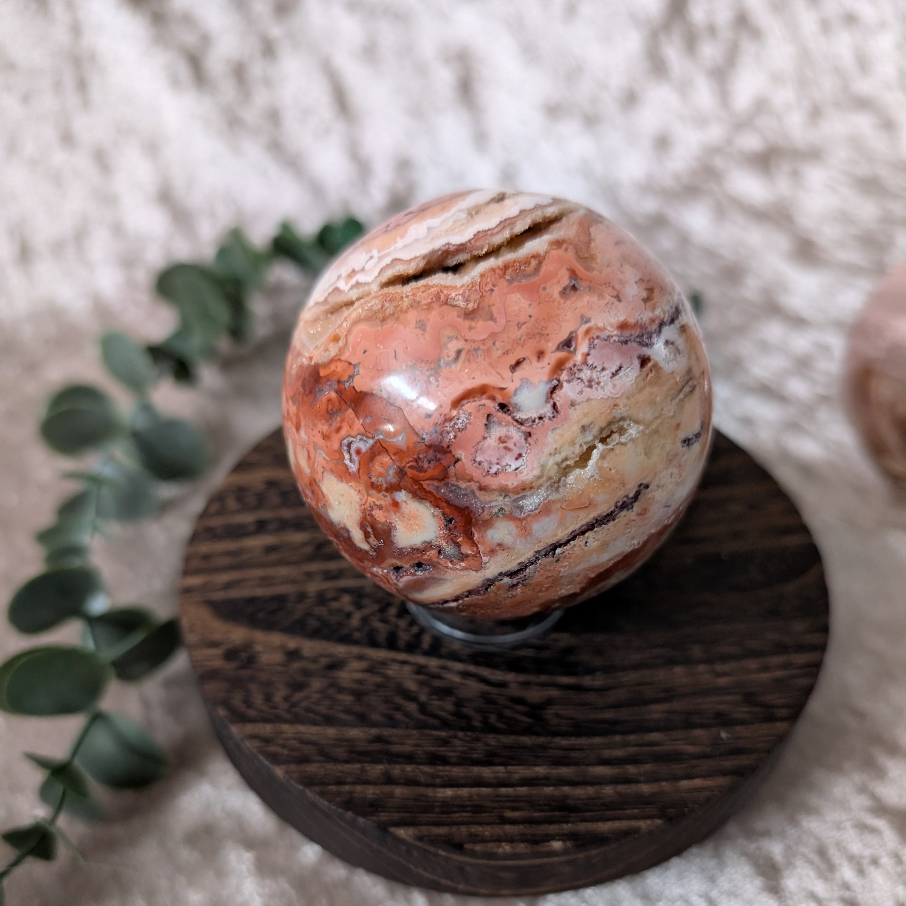 Side view of crazy lace agate sphere showing swirling banded patterns and polished stone surface