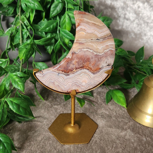 Polished Crazy Lace Agate crescent moon displayed on gold metal stand