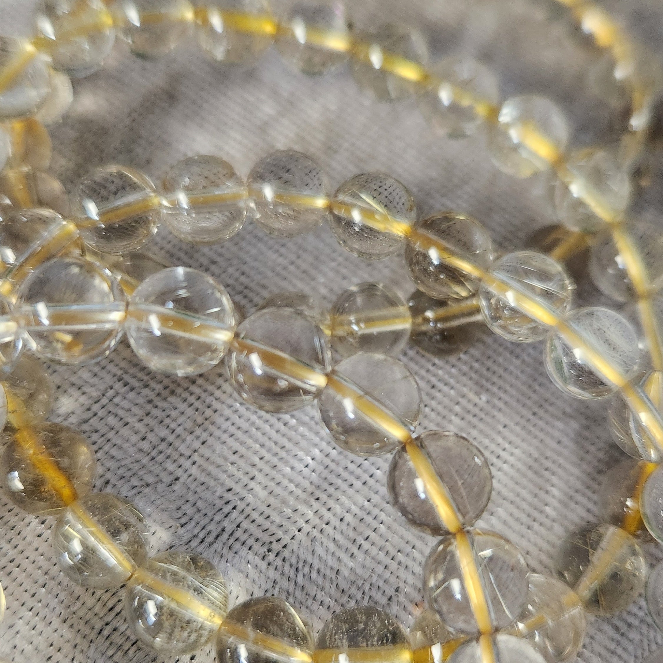Rutile Quartz bracelet beads displayed on a neutral velvet fabric