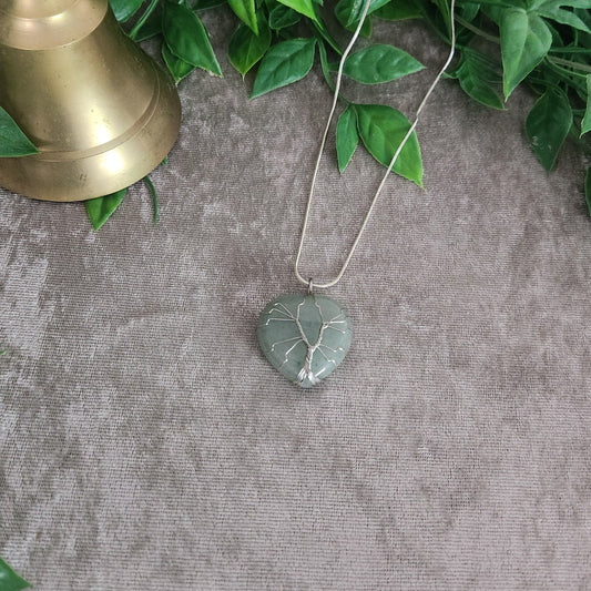 Green aventurine heart necklace with silver wire wrap on neutral fabric