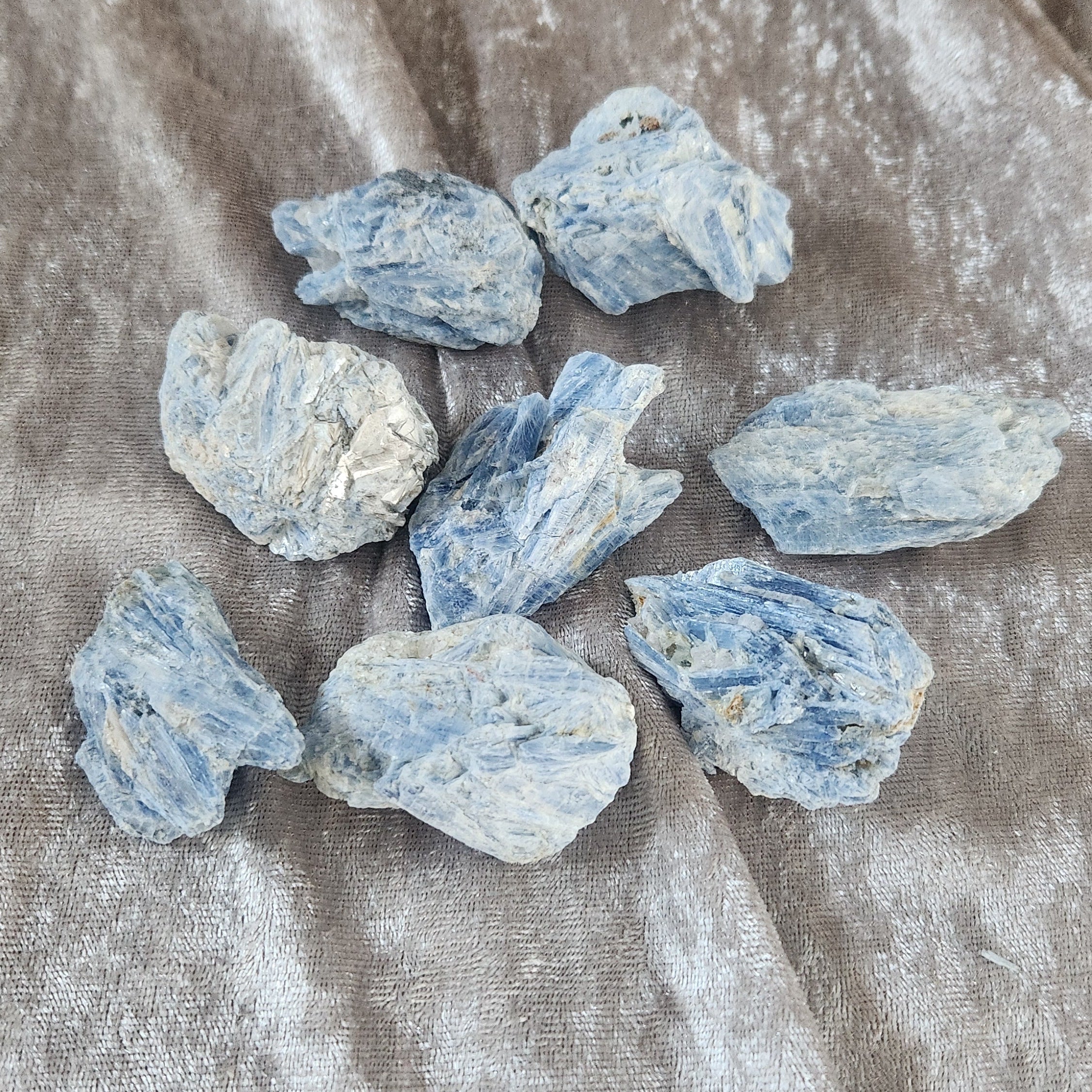 Pieces of raw kyanite with crystalline quartz on golden velvet background