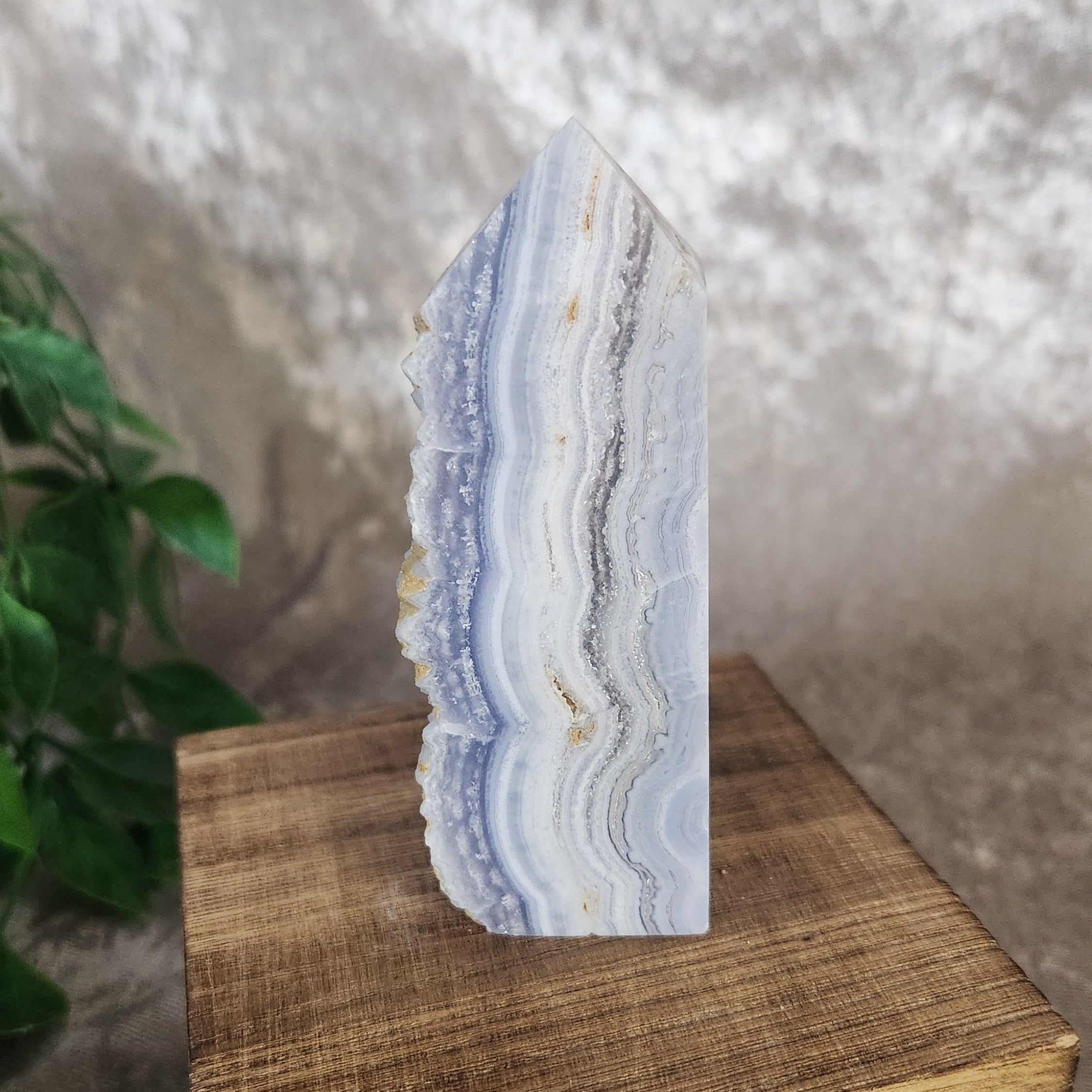 Blue lace agate tower with soft blue and white banding and natural druzy quartz pocket displayed upright on a wooden box