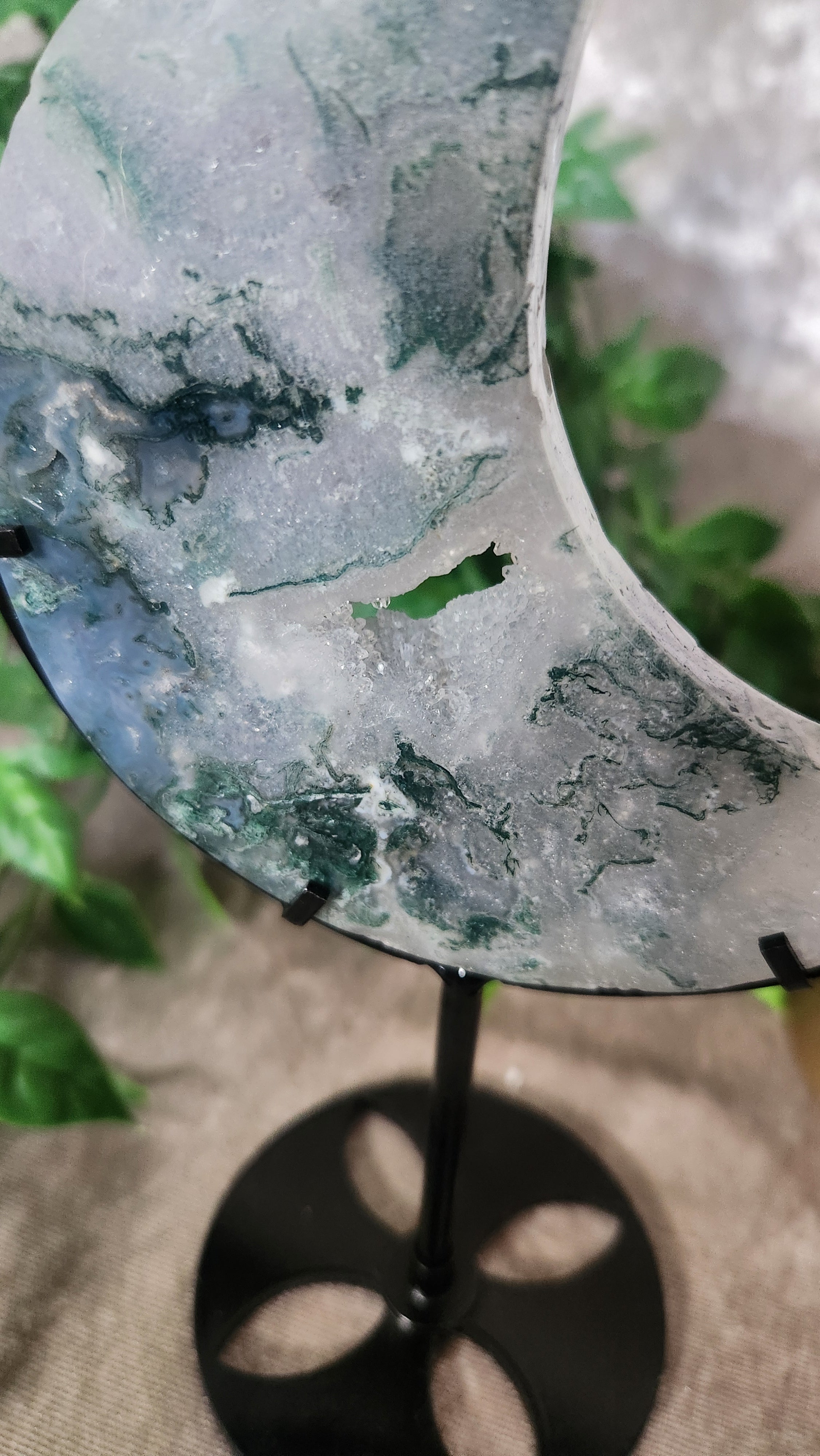 Moss Agate moon carving with natural green inclusions on stand