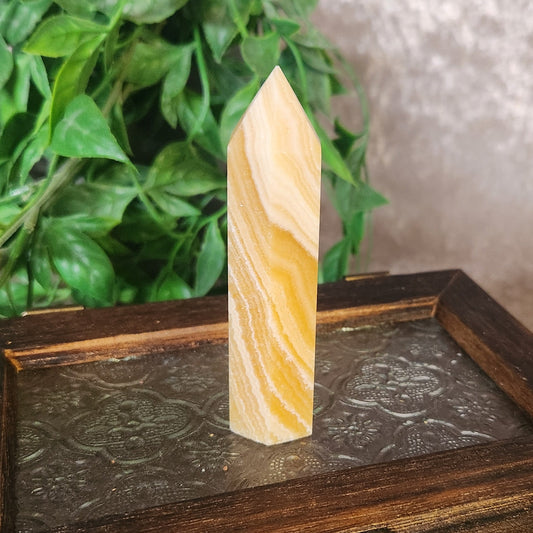 Polished orange banded calcite crystal tower showing natural orange and white banding