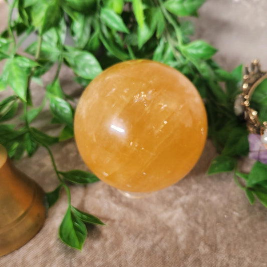 Honey Calcite sphere with warm golden tones on decorative stand