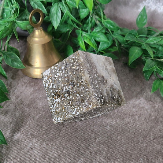 Ocean jasper cube with natural orbicular patterning photographed on neutral fabric