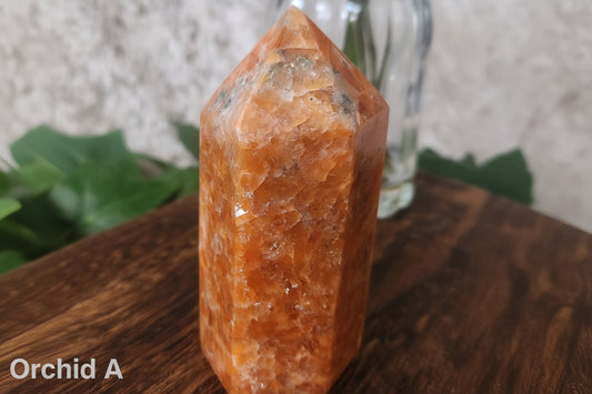 Orchid Calcite generator with natural black tourmaline inclusions on wooden surface