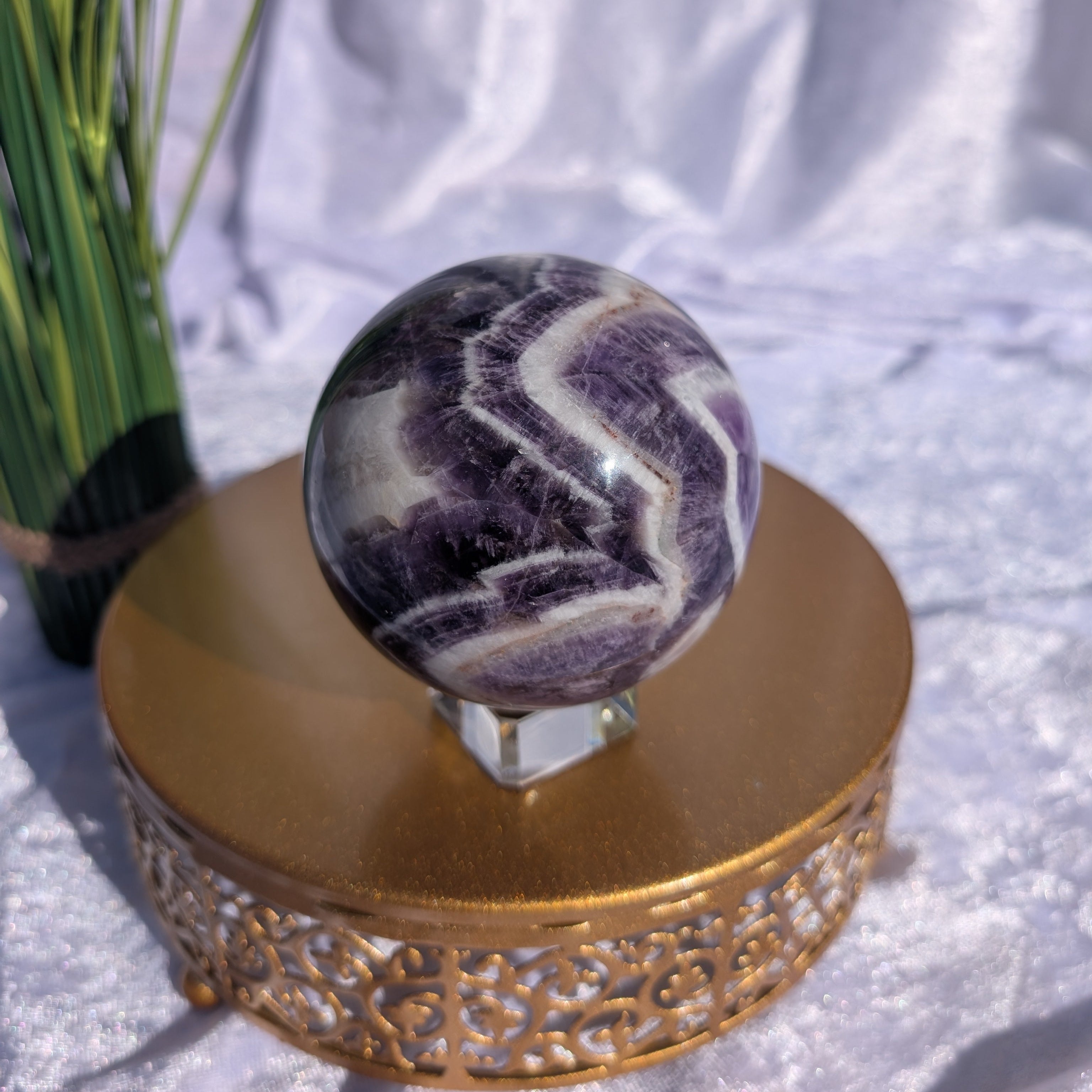 Chevron Amethyst Sphere with strong banding displayed in natural light with white velvet background