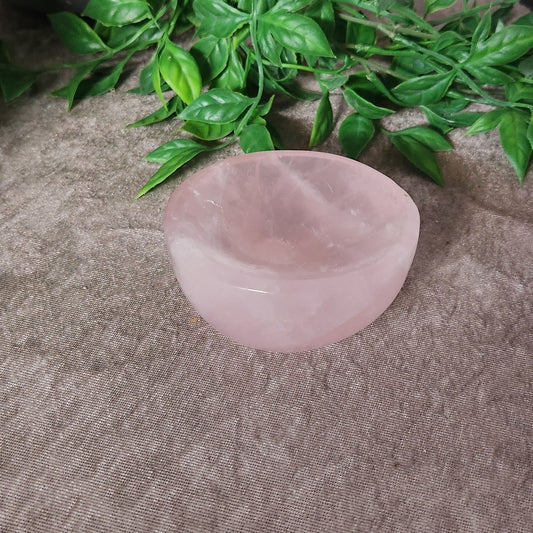 Polished rose quartz bowl with soft pink tones shown from above on neutral fabric background