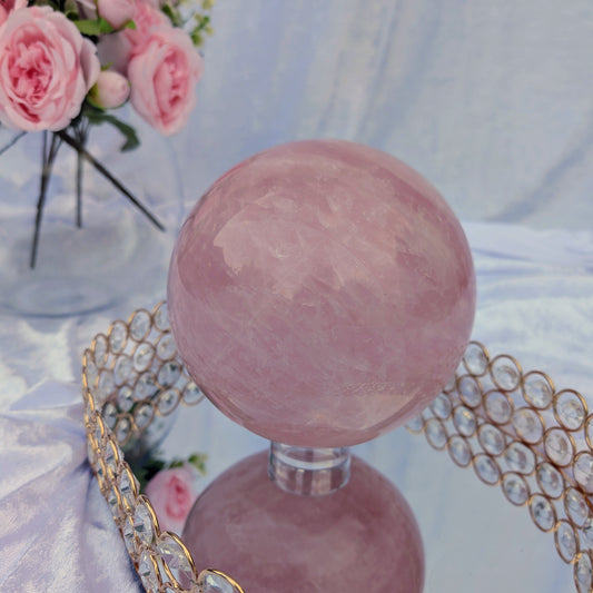 Rose Quartz Sphere – 4.38 kg statement crystal on mirrored tray with pastel floral styling, soft ambient lighting.