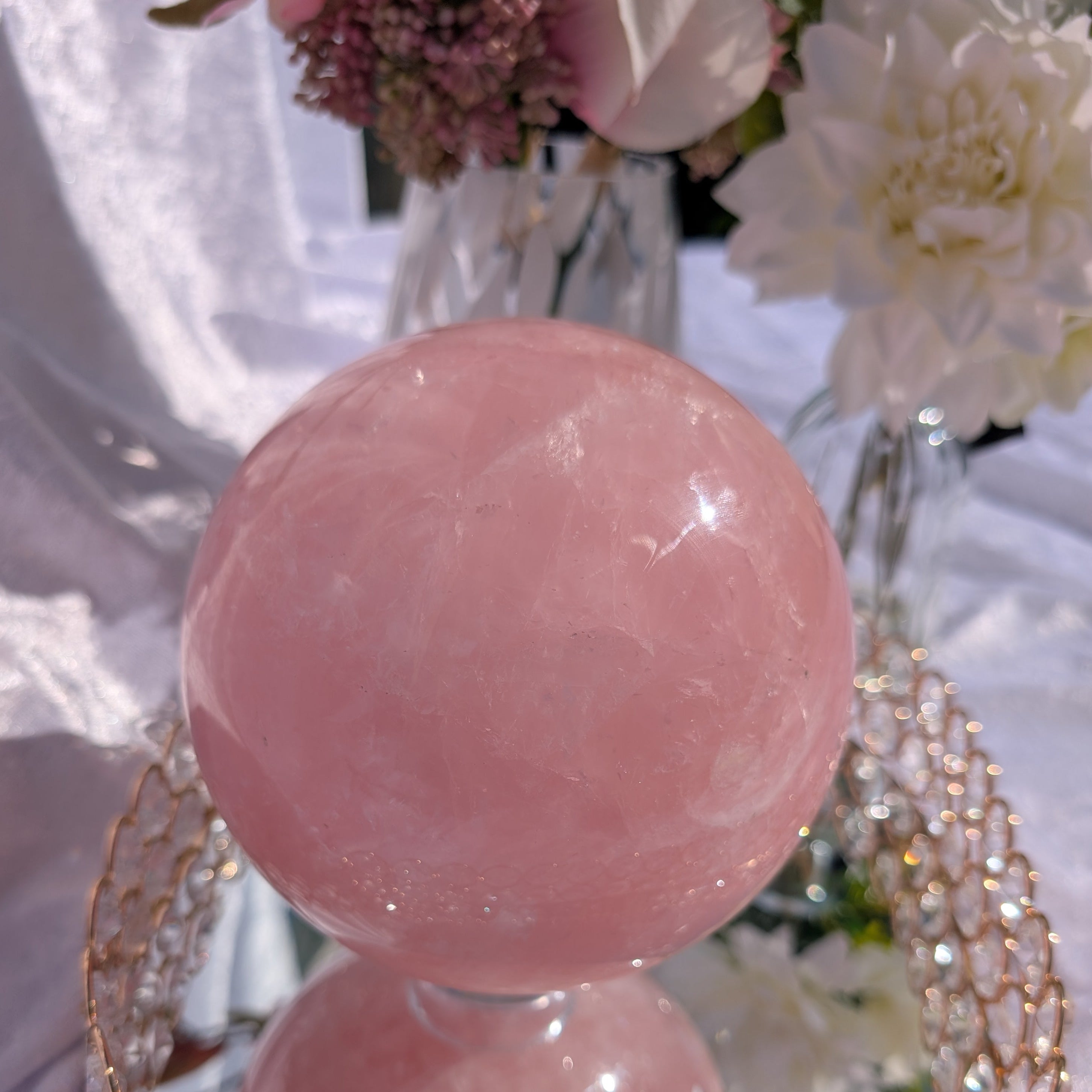 Rose Quartz Sphere – 4.38 kg large statement sphere photographed in natural light with floral décor and mirrored base.”