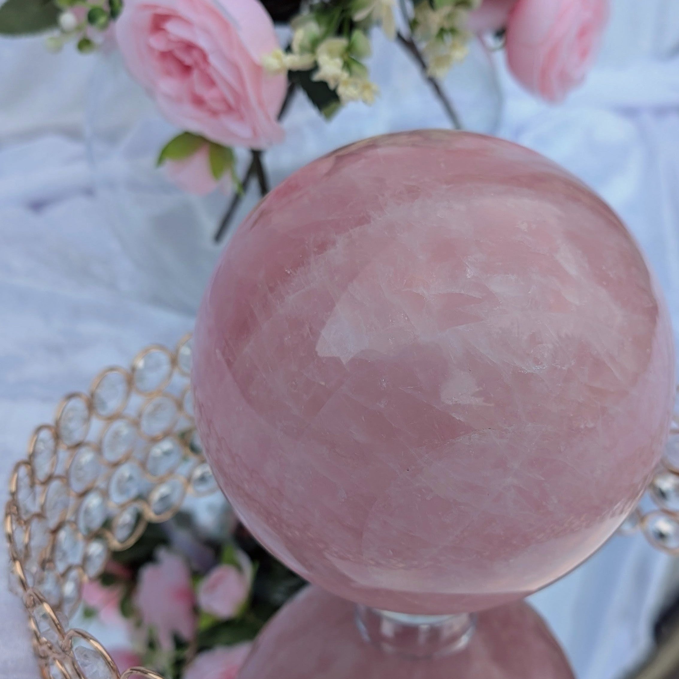 Rose Quartz Sphere – Large 4.38 kg piece displayed on crystal tray with soft pink florals and sunlight reflections.