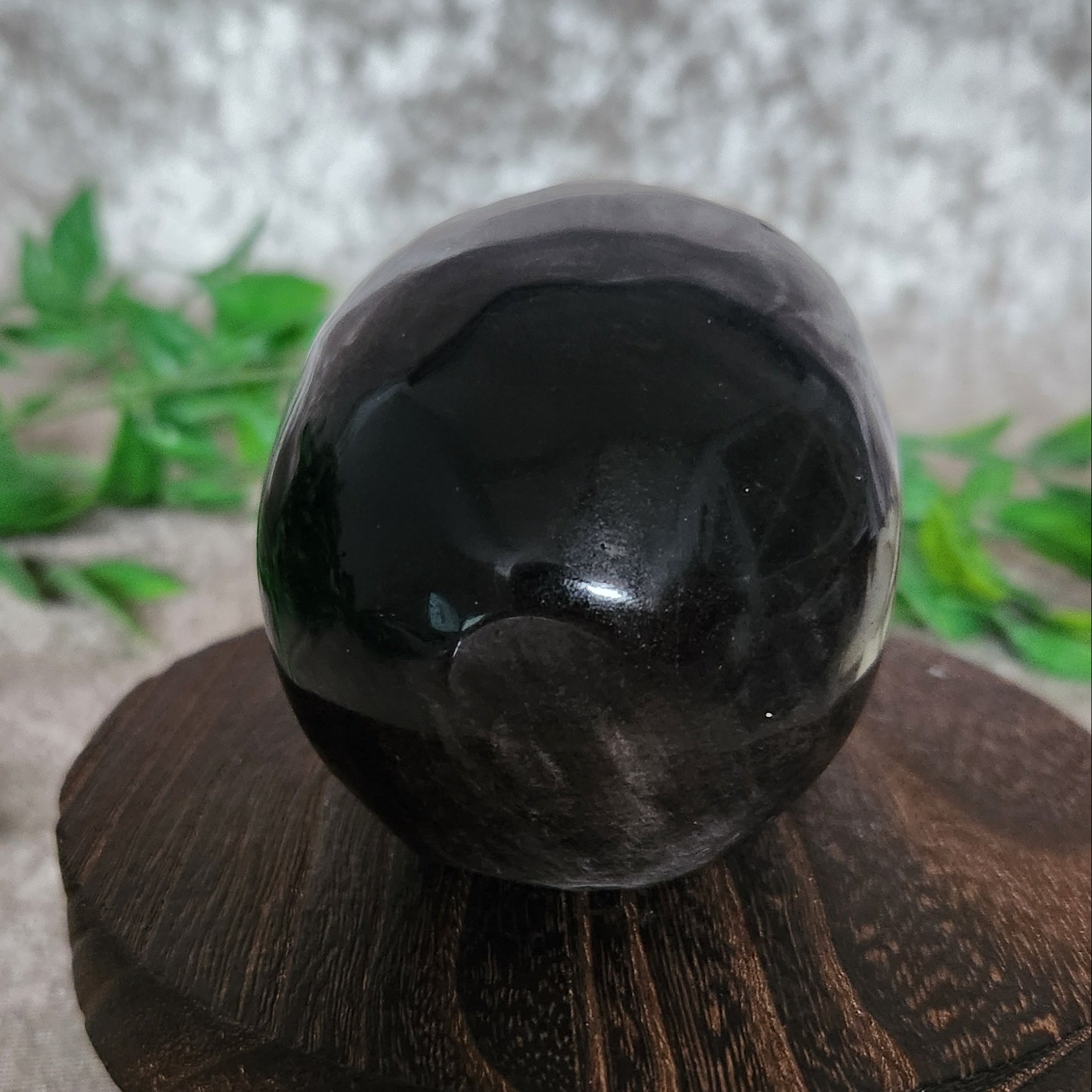 Crystal skull carved from Silver Sheen Obsidian — rear angle displaying polished surface and reflective silver layers.