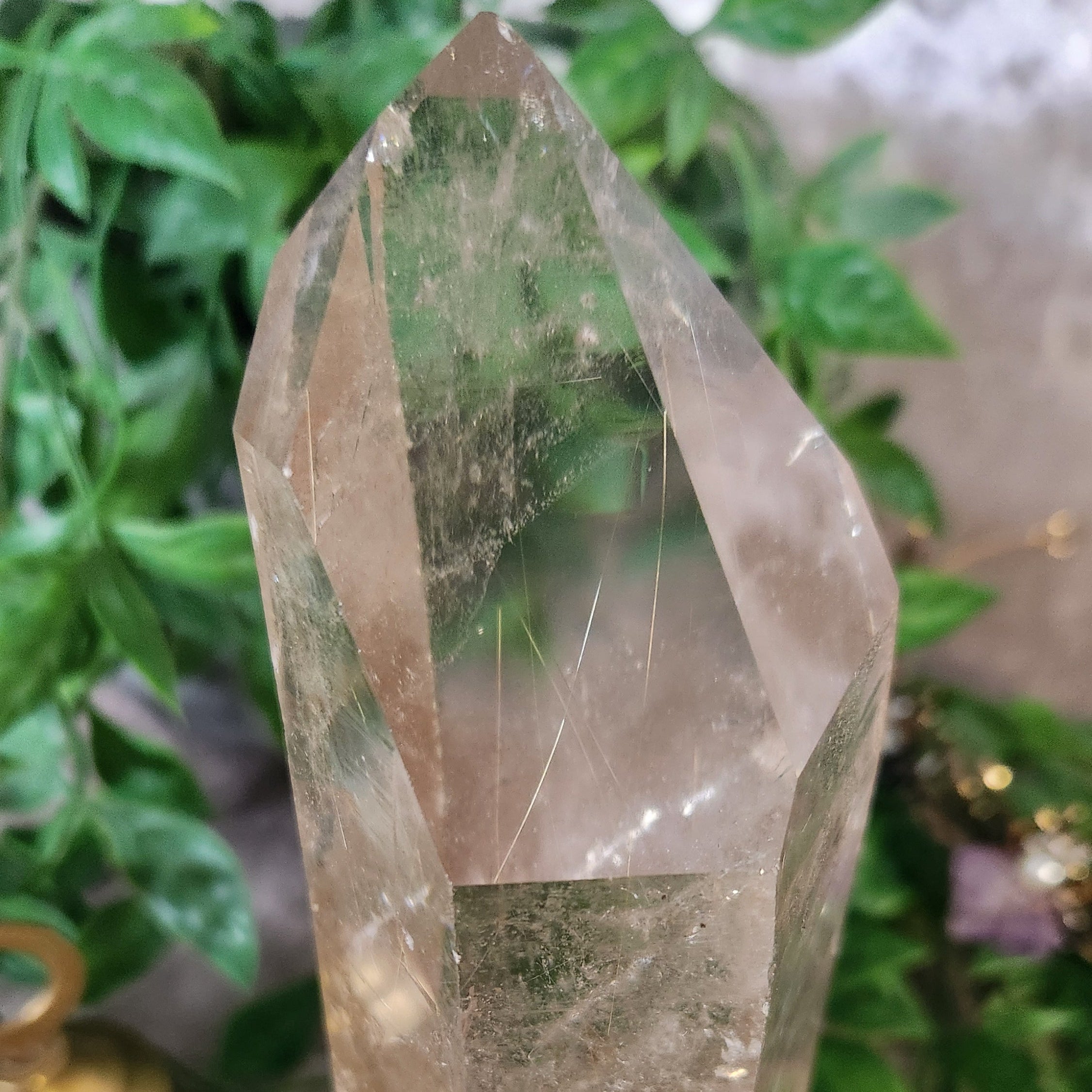 Clear quartz crystal point on stand with smooth polished faces and silver rutile inclusions