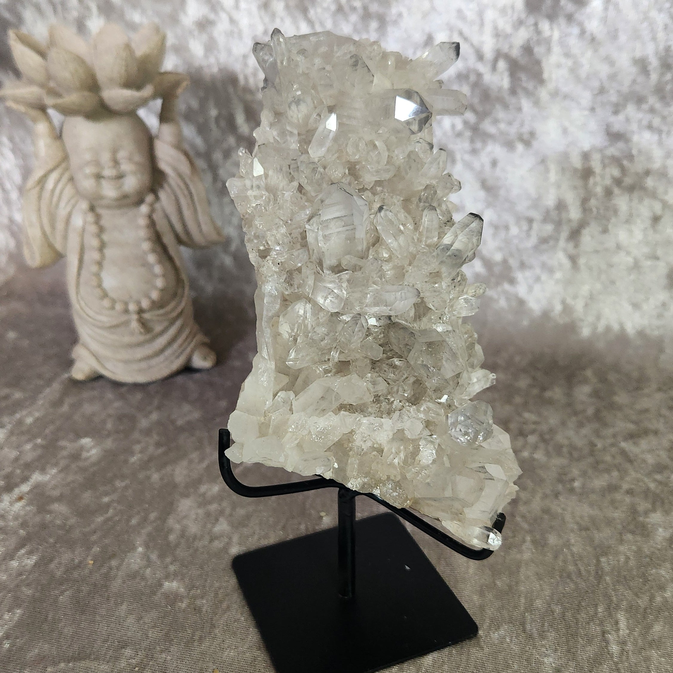 Light smoky lemurian quartz cluster on black metal stand