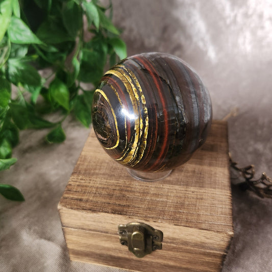 Polished Tiger Iron sphere with natural red, gold, and black banding