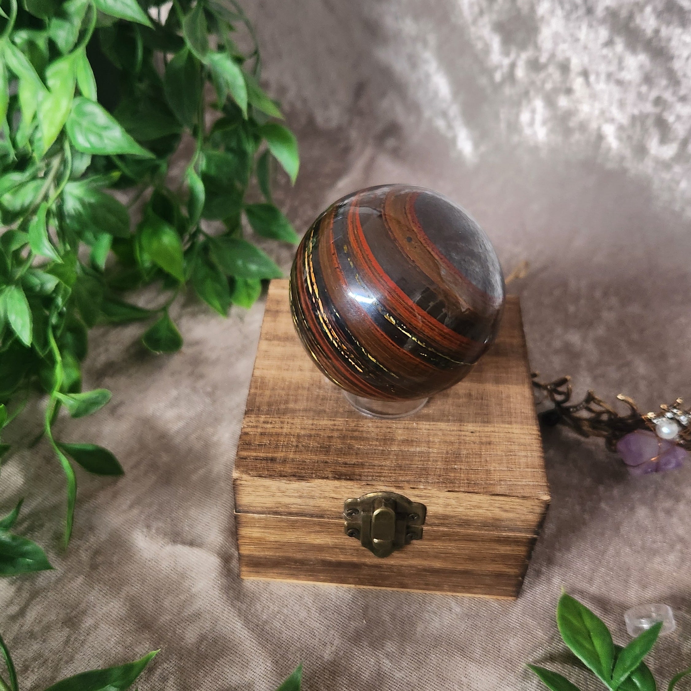 Natural Tiger Iron stone sphere photographed on wooden display box