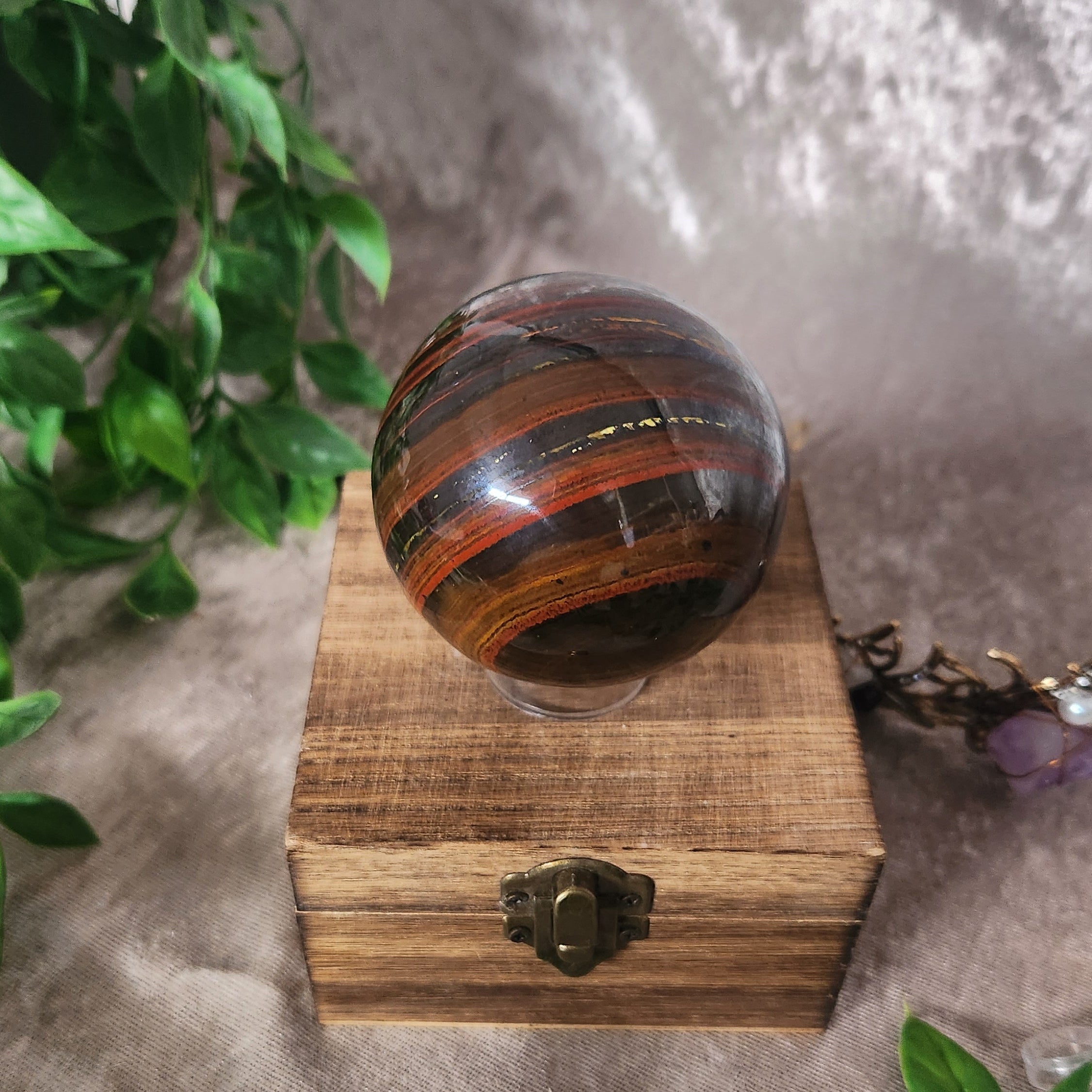 Close-up of polished Tiger Iron sphere highlighting rich earthy banding