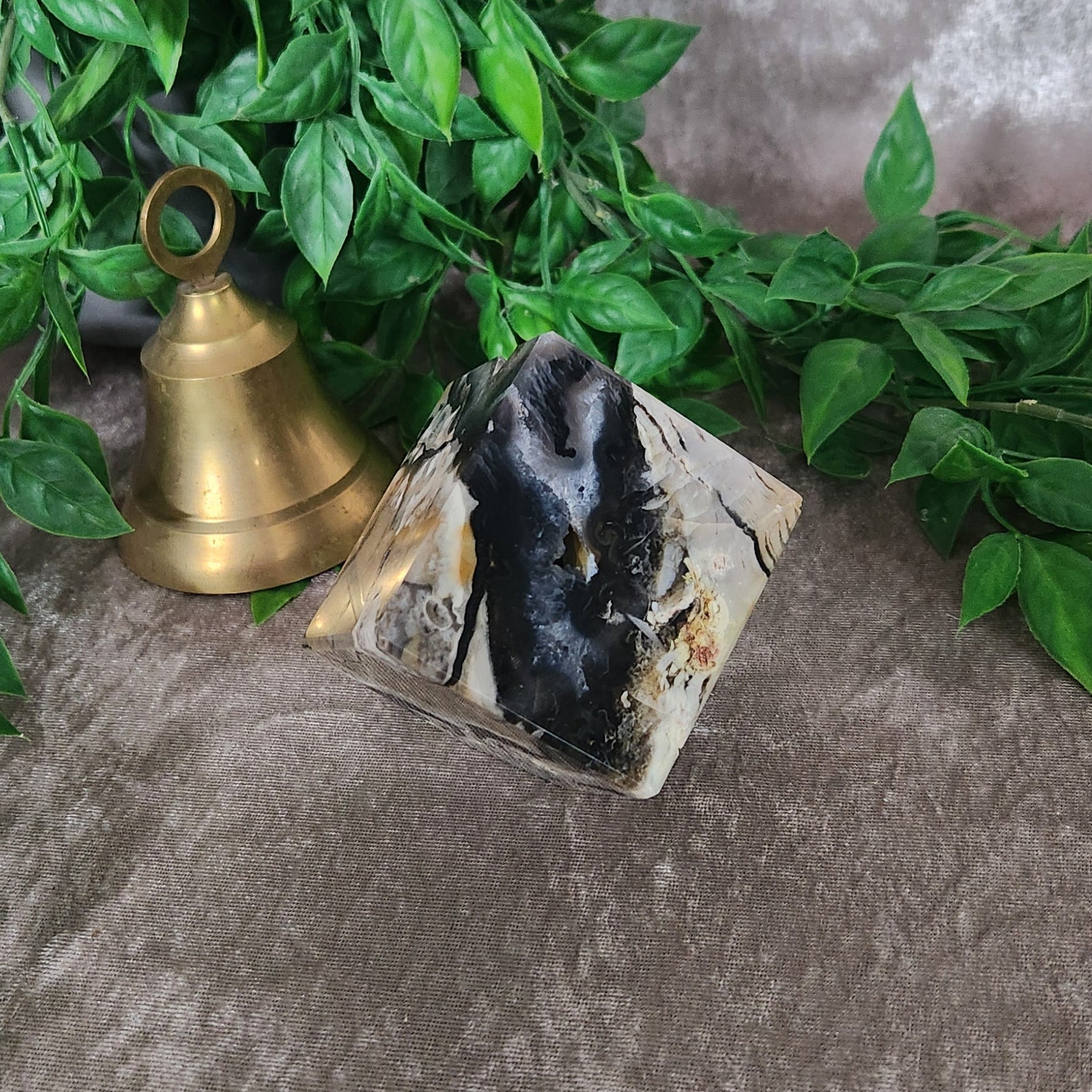 Volcano agate cube with green and earthy banding photographed on neutral fabric