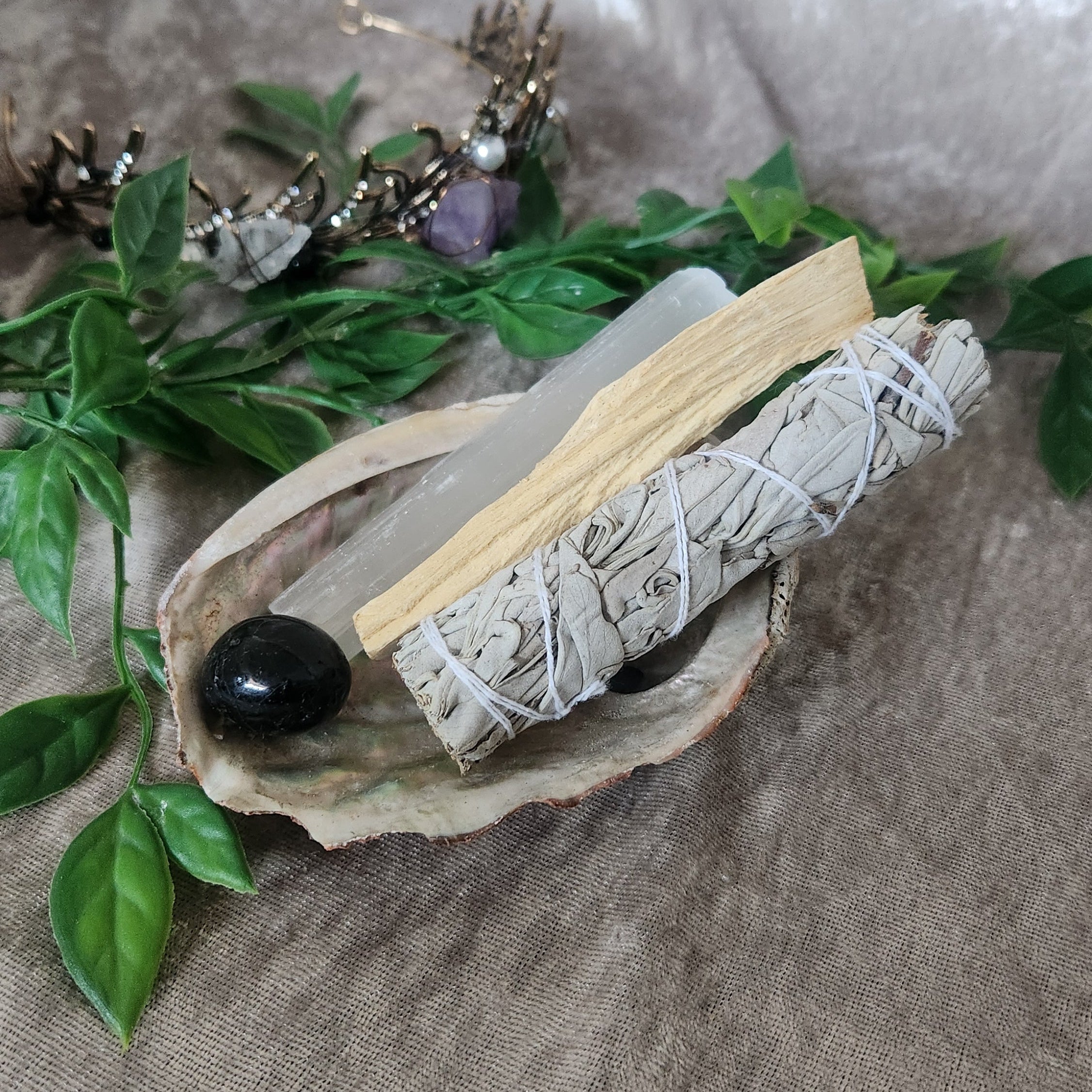 Spellbound protection kit with white sage, palo santo, and abalone shell presented in a natural drawstring pouch, styled for spiritual cleansing rituals