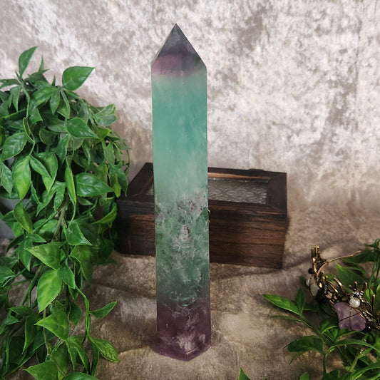 Polished rainbow fluorite tower showing translucent green and violet layers