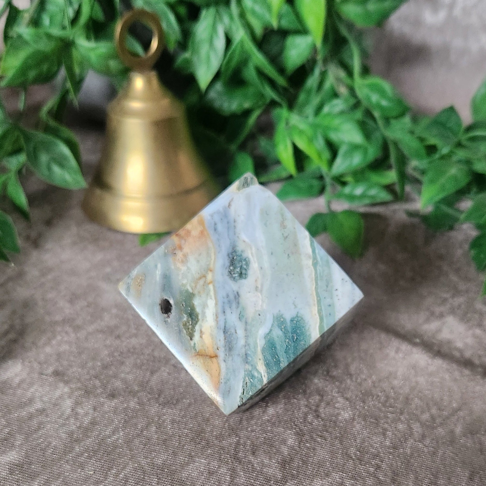Polished sea jasper cube photographed on neutral fabric background
