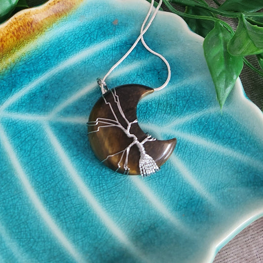 Tiger eye moon necklace with silver wire wrap on teal background