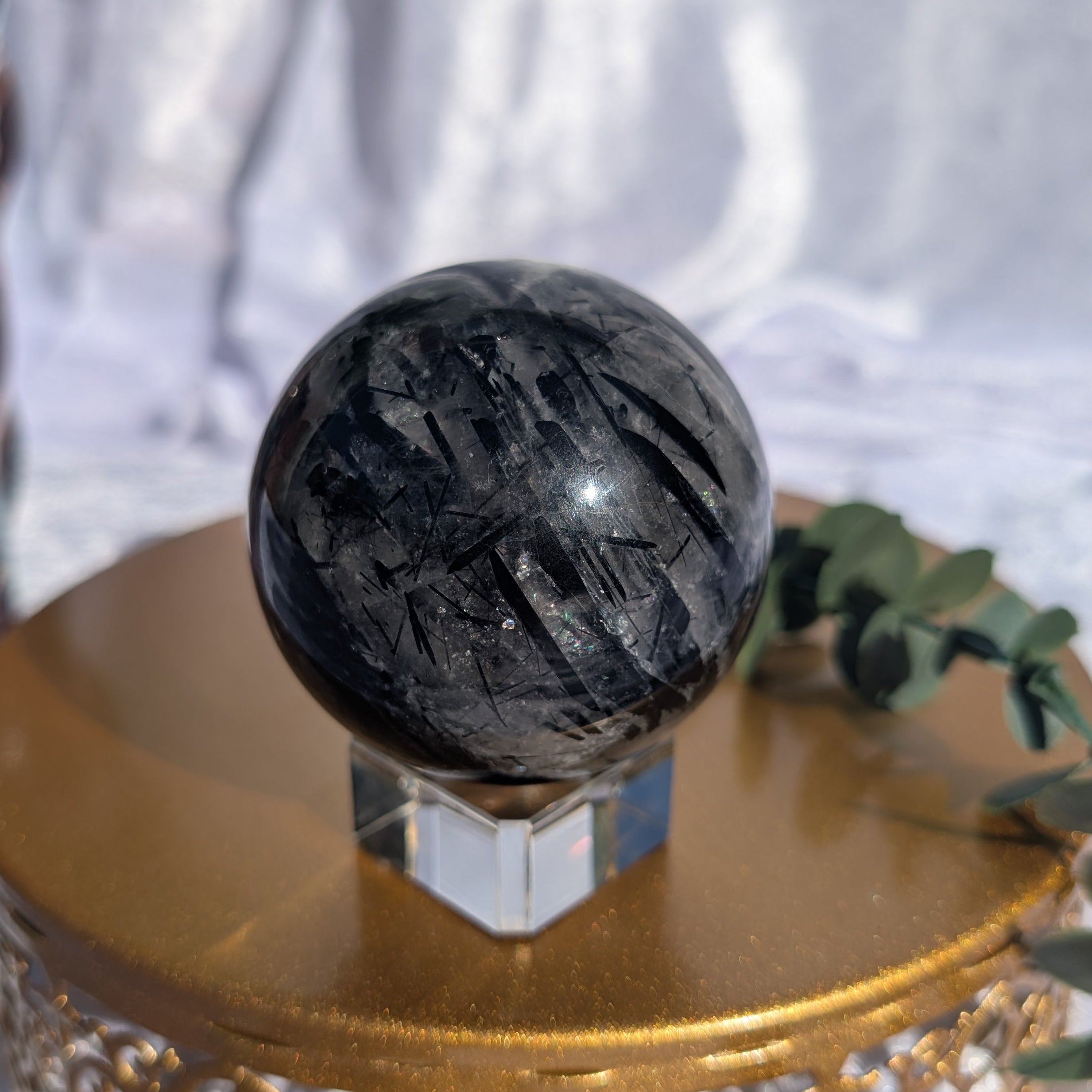 Natural Tourmalinated Quartz crystal sphere on display stand
